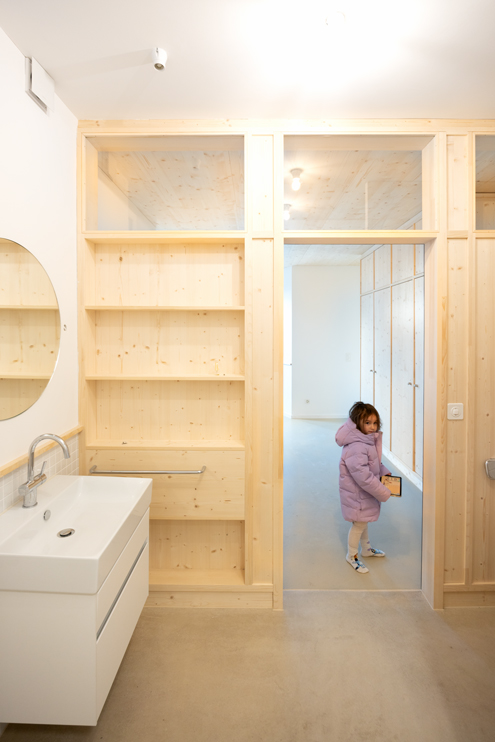 Küsnacht Kellerausbau neues Bad mit im oberen Bereich verglasten Holz-Regal-Trennwand. Der Anhydrit Gussboden ist in der ganzen Wohnung eingebracht und zieht sich auch ins Bad hinein. Das Bad ist multifunktional und dient auch als Durchgang in den neuen Kelleranbau.